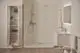 Badezimmer mit modernem Duschsystem, ausgestattet mit einem Brausethermostat, Glasduschtür und minimalistischer Optik. Unterbringungsmöglichkeiten für Kosmetik und Handtücher sichtbar. Ideal Standard.